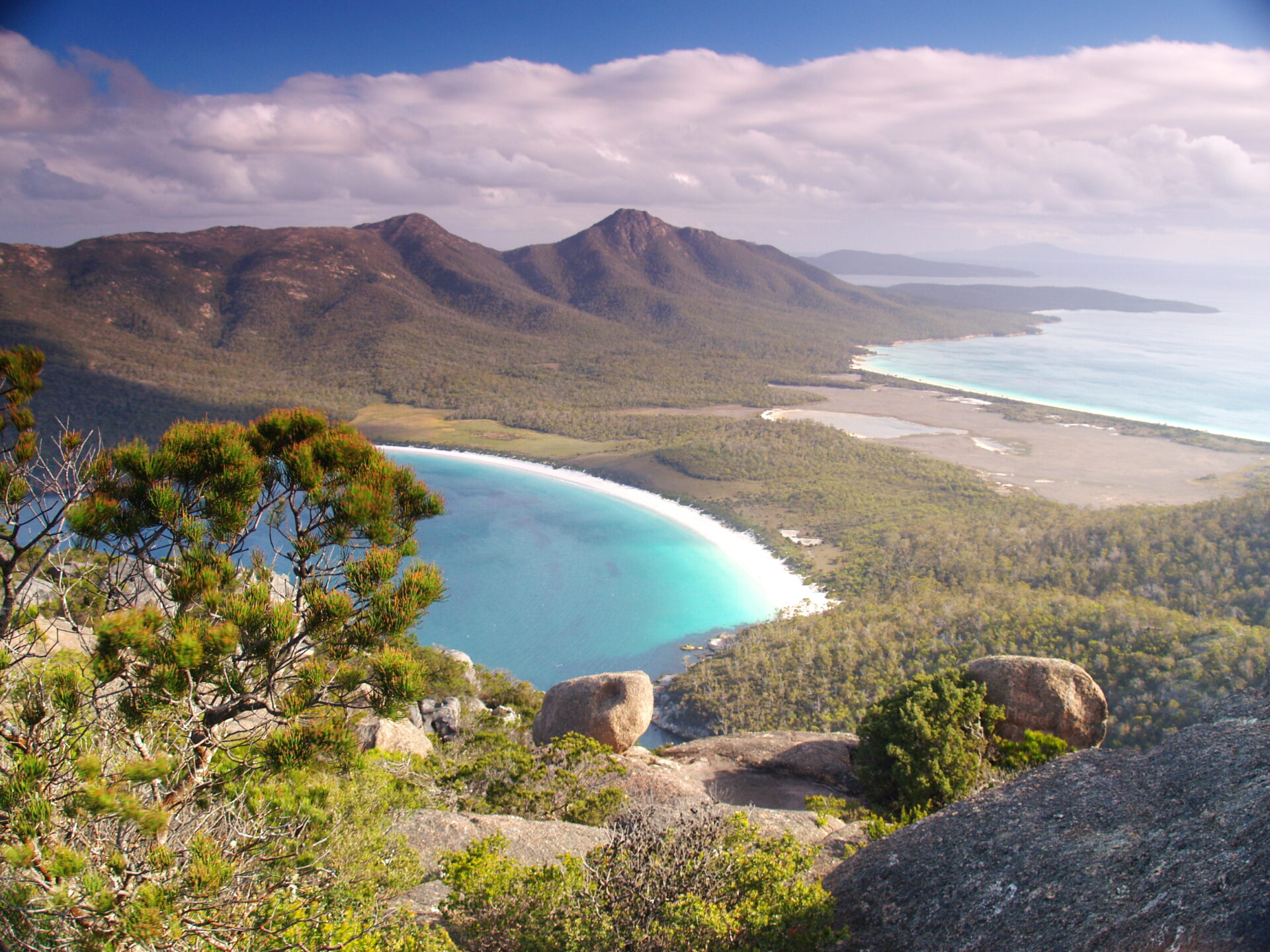 Wineglass Bay im Freycinet National Park Tasmanien mit halbmondförmigem weißem Sandstrand, türkisfarbenem Wasser und rosaroten Hazards-Bergen – ikonischster Strand Australiens.
