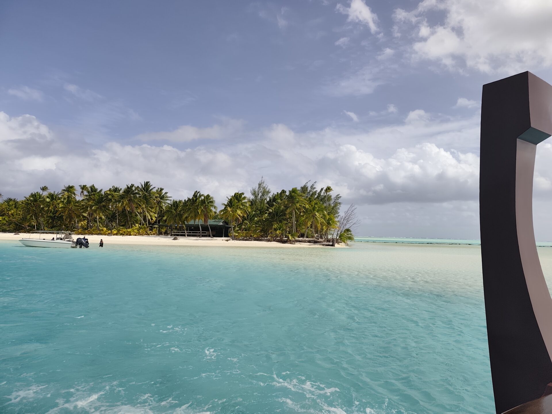 Kristallklare türkise Lagune von Aitutaki mit weißem Sandstrand, Palmen und flachem kristallklarem Wasser, ideal zum Schnorcheln und Schwimmen in den Cookinseln.